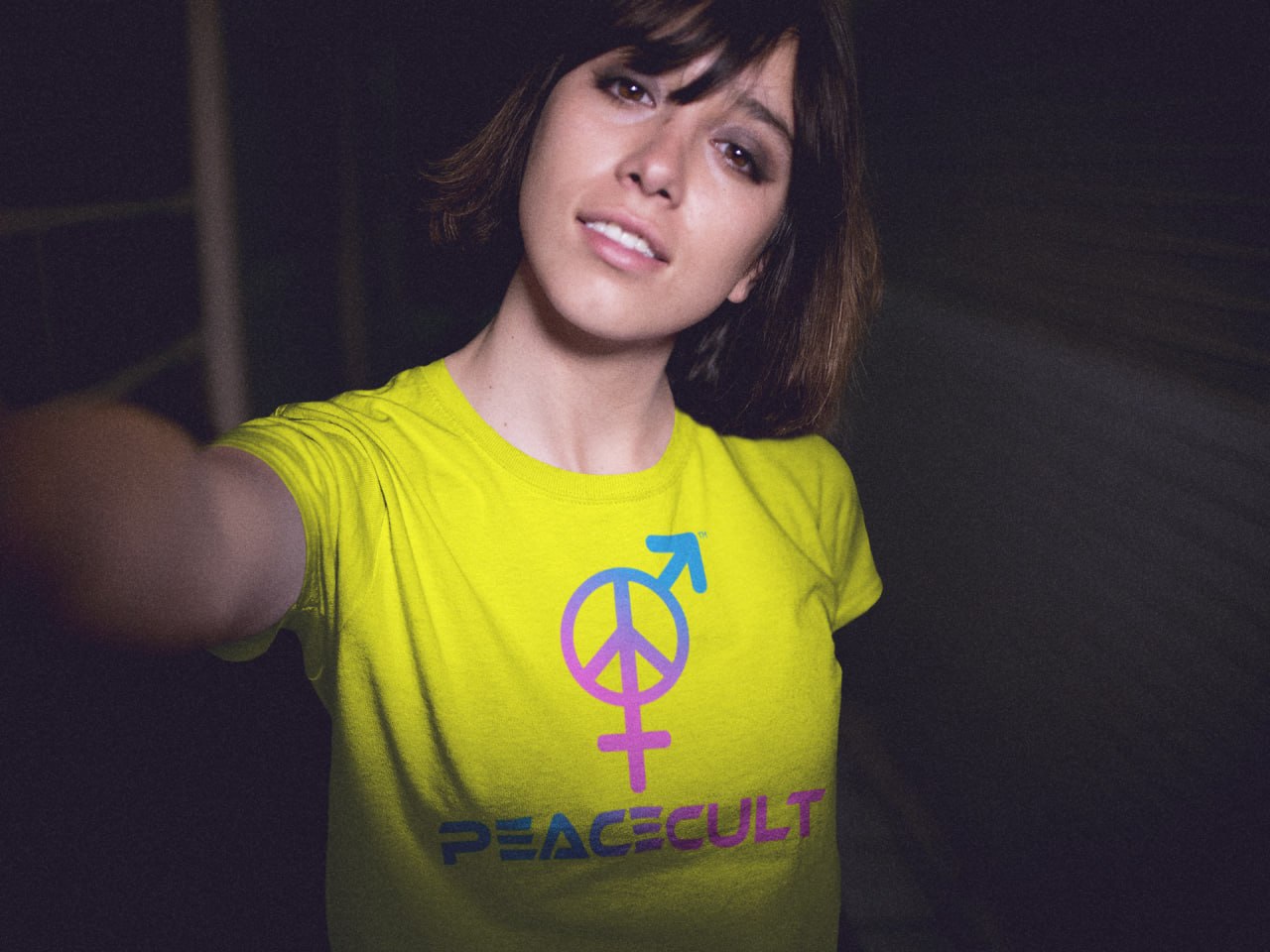 Woman taking a night-time selfie wearing a neon yellow PEACECULT t-shirt